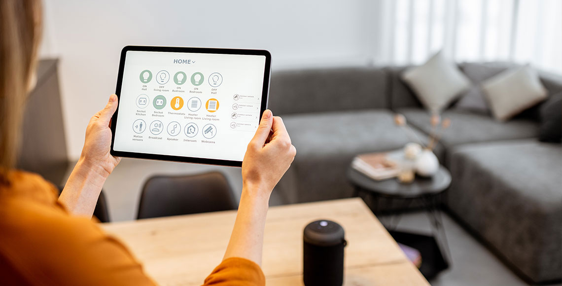 A woman using her iPad to interact with a smart home control panel, in her home office.