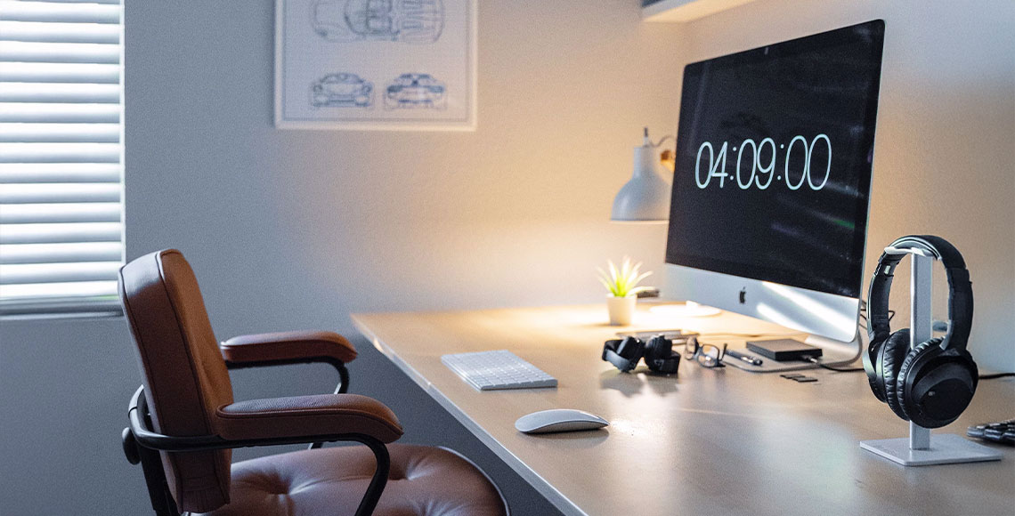 A stylish home office desk with a computer, headphones, and stationery, designed with a clean and productive setup in mind.